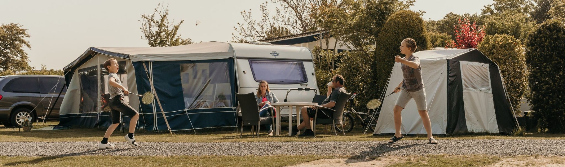 Kinderen spelen badminton bij de caravan op camping Kotestee in Ouddorp.