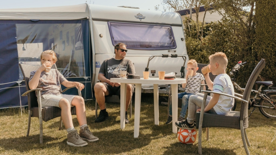 Gezin zit gezellig bij de caravan op camping Kotestee in Ouddorp.