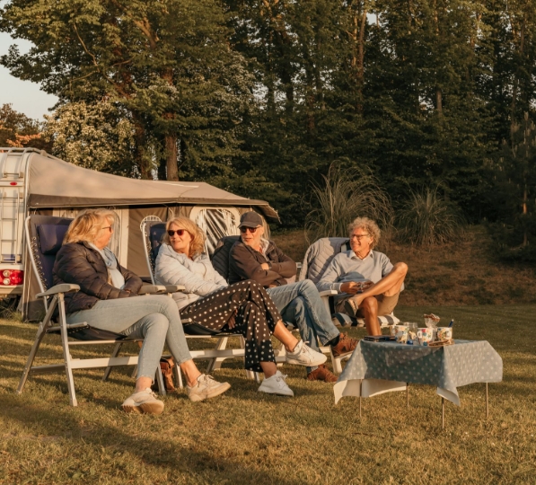 Campinggasten zitten gezellig bij de caravan op camping Kotestee in Ouddorp.