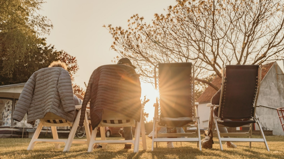 Campinggasten zitten in ligstoelen in de avondzon op camping Kotestee in Ouddorp.