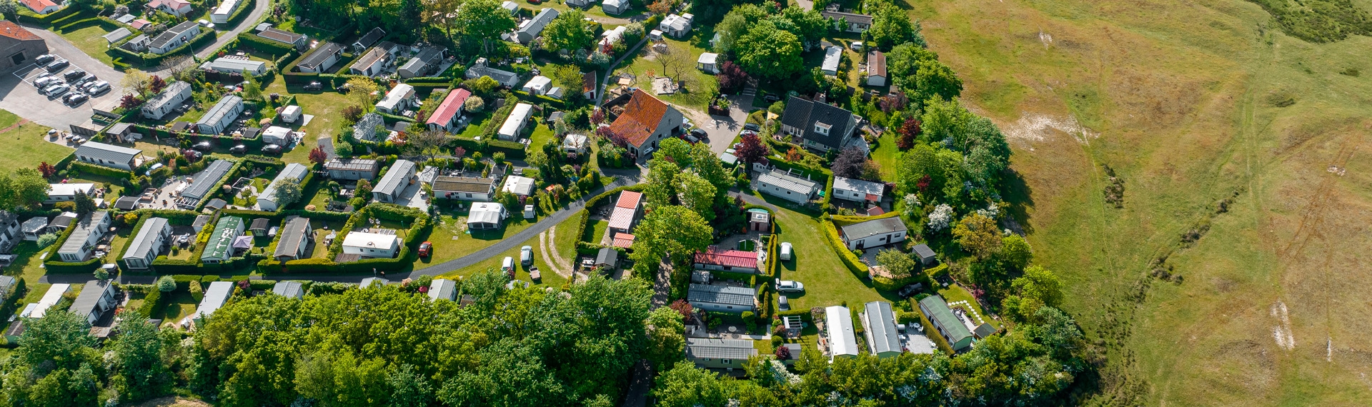 Panoramisch dronebeeld van de camping langs de duinrand.