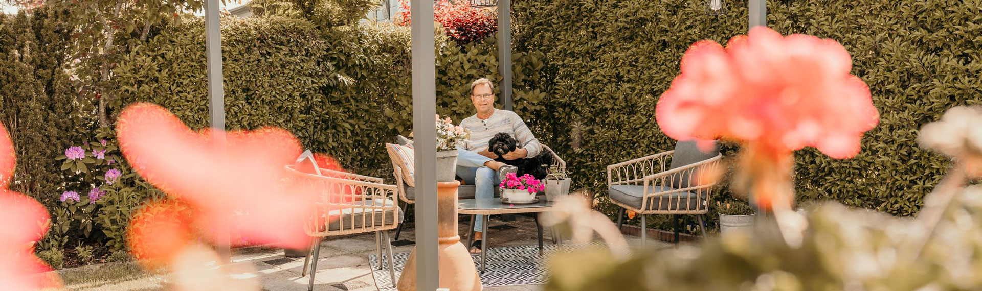 Campinggast met hond zit in de tuin bij een stacaravan op camping Kotestee in Ouddorp.