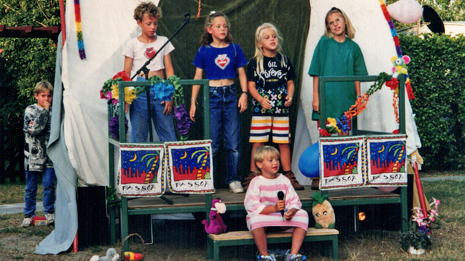 Kinderen voeren een playbackshow op tijdens een zomerse campingactiviteit in de jaren negentig.